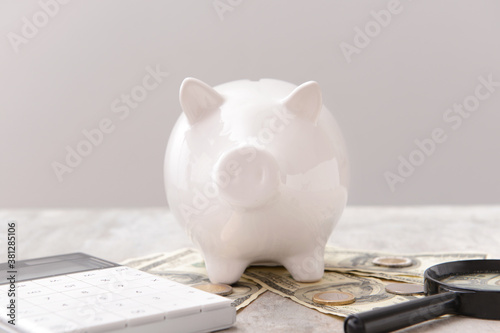 Piggy bank with money, calculator and magnifier on grey background. Concept of pension