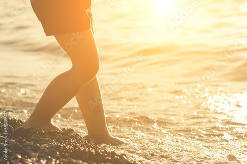 Kids legs standing on the seashore on sunset. Warm summer evening on resort.