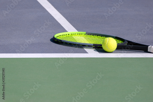 Hard tennis court with tennis racket and ball on it. Bi-color - green and purple sports court and composition of tennis equipment on white lines. Sports background with copy space