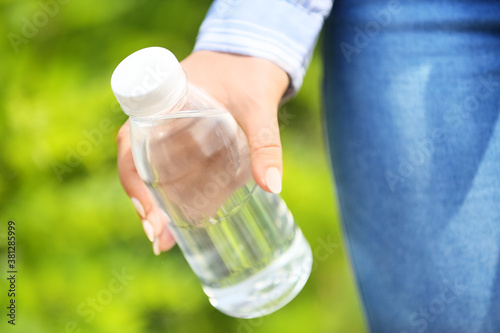 Woman with bottle of water outdoors, closeup