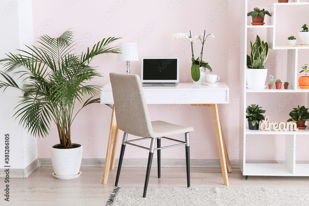 Fototapeta premium Stylish interior of room with green houseplants and workplace