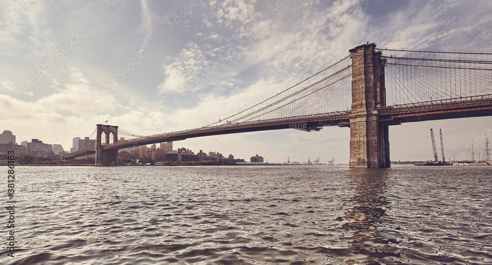 Retro toned picture of Brooklyn Bridge against the sun, New York City, USA.