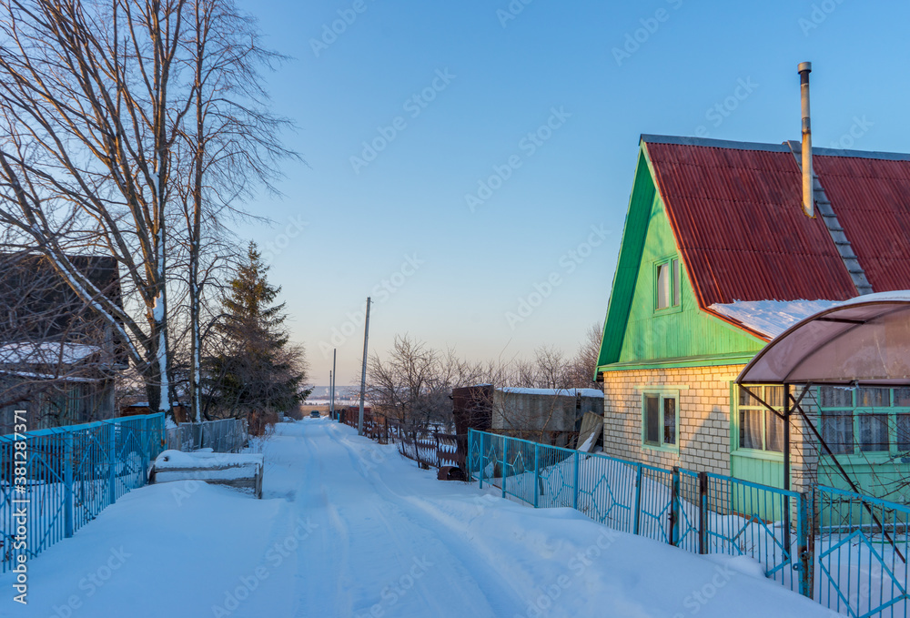 Street in country village covered with snow and left for the winter brick cottage house on wintery evening at sunset. Russian dacha concept Street in country village covered with snow and left for the winter brick cottage house on wintery evening at sunset. Russian dacha concept