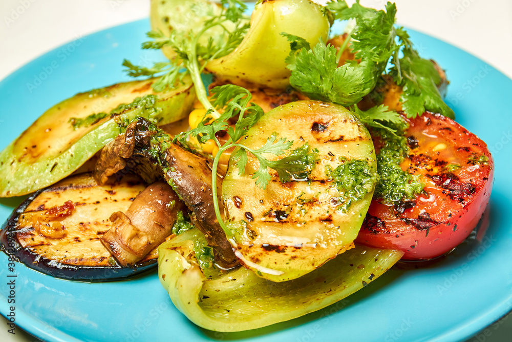 Grilled vegetables bell pepper, zucchini, tomato, mushrooms, red onion on the blue plate Grilled vegetables bell pepper, zucchini, tomato, mushrooms, red onion on the blue plate