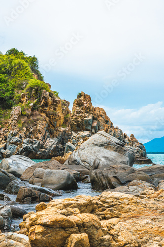 Beauty panorama edged shabby sea cliff cumulus cloud sky mountain island background. Gray brown stone rock texture vivid colour photo. Concept of geology, tourism after pandemic, power in nature © NOVOZHILOV ANDREI