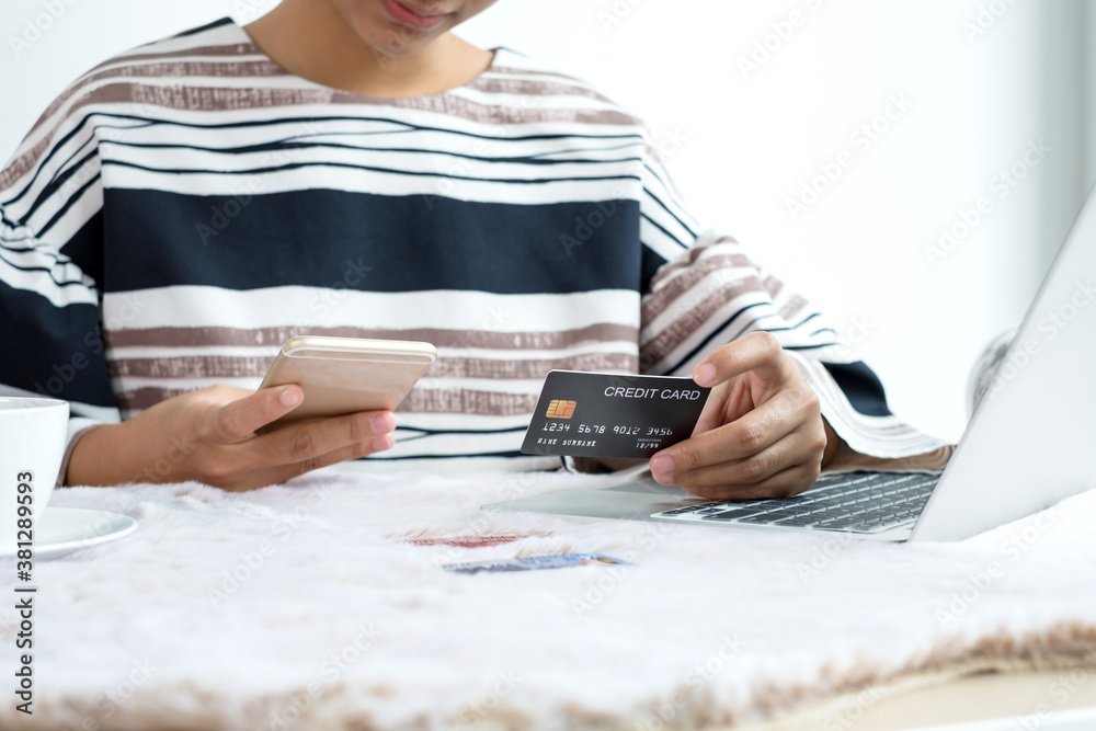 Fototapeta premium The businesswoman's hand is holding a credit card and using a smartphone for online shopping and internet payment in the office