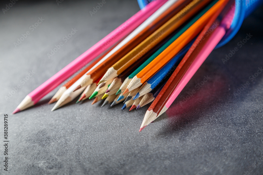Pens and pencils in metal holder in front of wall background Pens and pencils in metal holder in front of wall background