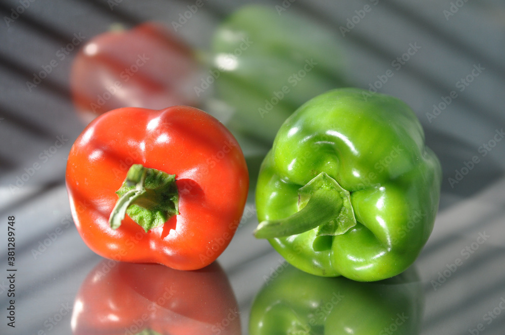 Green and red peppers on a stainless steel surface.