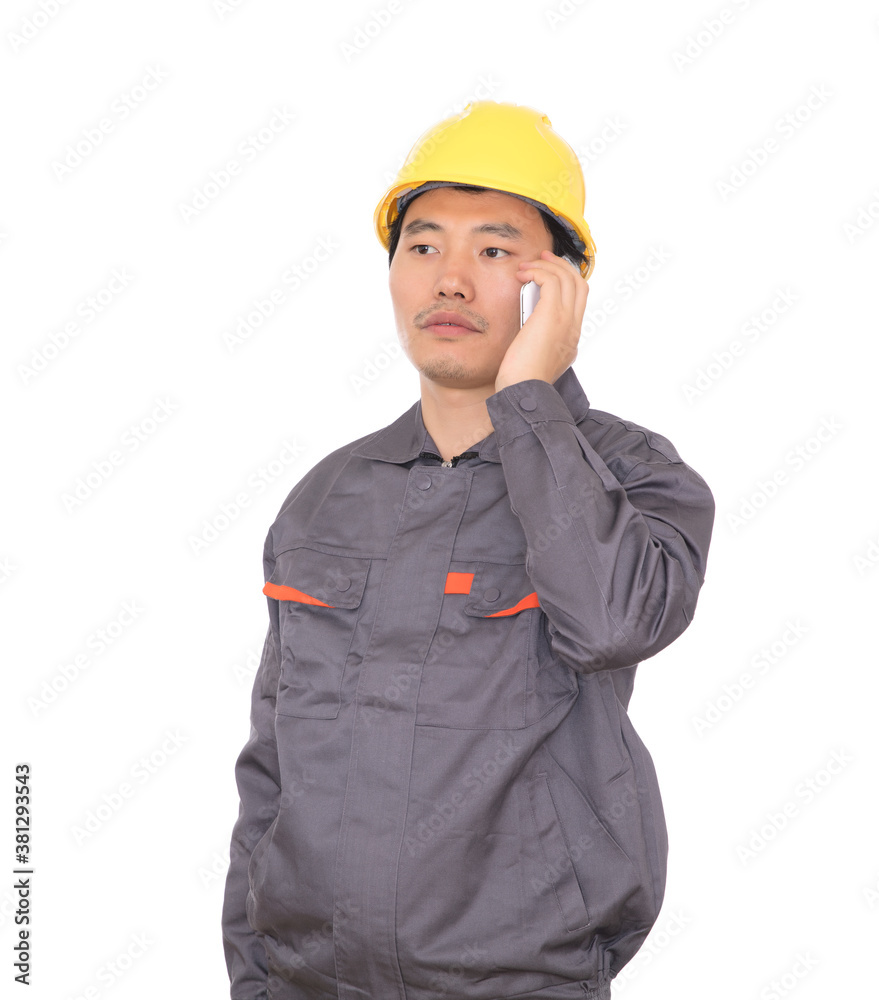 Migrant worker wearing yellow hard hat in front of white background is calling home