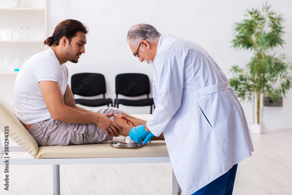 Obraz premium Leg injured man visiting old doctor in first aid concept