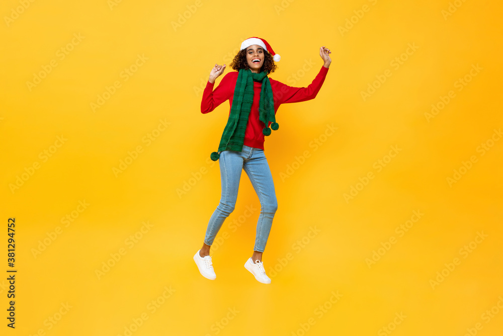 Excited pretty woman in Christmas attire jumping on isolated yellow studio background