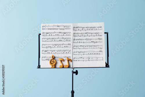 Fotografija Music sheets with notes on stand against color background
