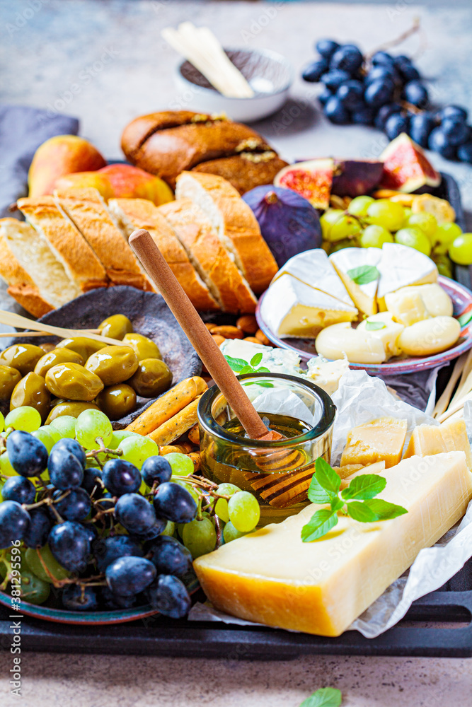 Cheese plate served with fruits, honey and snacks, close up. Assorted cheese background.