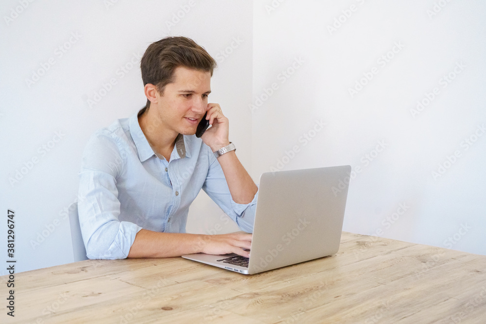 young man sitting with laptop talking on the phone young man sitting with laptop talking on the phone