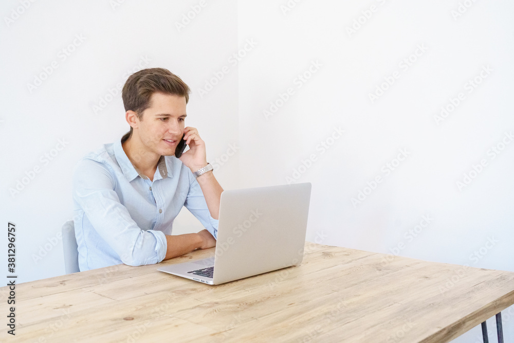young man sitting with laptop talking on the phone young man sitting with laptop talking on the phone