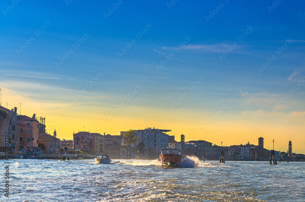 Yacht boats racing sailing on water of Venetian lagoon between wooden poles. Venice city coast with buildings background, Veneto region, Northern Italy Yacht boats racing sailing on water of Venetian lagoon between wooden poles. Venice city coast with buildings background, Veneto region, Northern Italy
