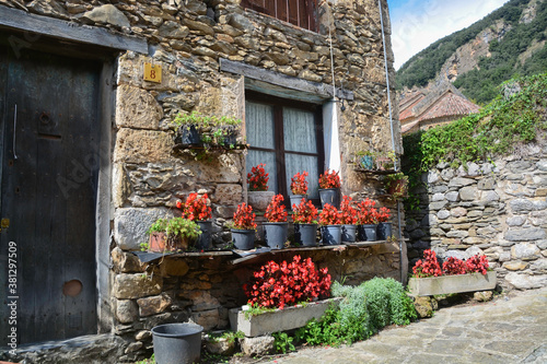 BEGET, CATALONIA, SPAIN, EUROPE, SEPTEMBER 2020. Beautiful stone house with red flowers around the door in the picturesque medieval town of Beget, which is an important tourist place in Catalonia.