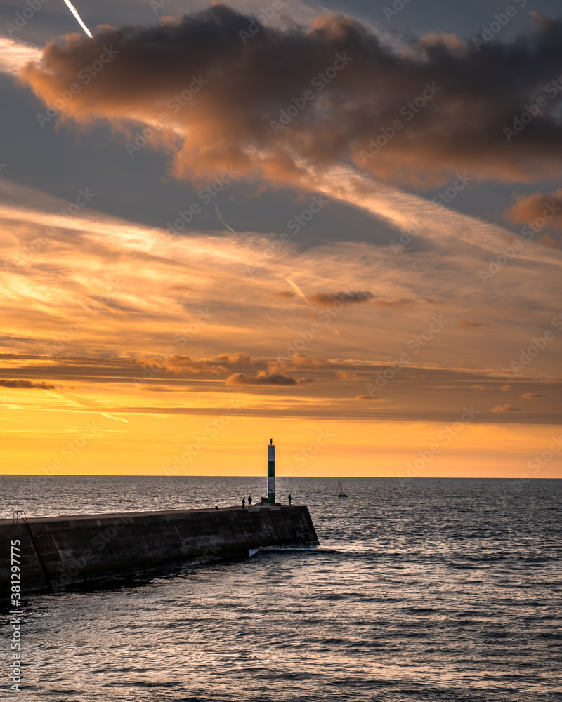 Aberystwyth lighthouse at sunset, while fisherman try to catch fish before the weather turns for Autumn.
