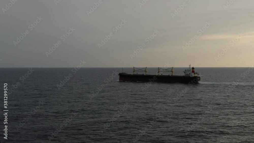 Large cargo ship. A bulk carrier carries cargo across the ocean. Transportation. Delivery. Logistics. A large ship for transporting. Sunset. Silhouette. Aerial 4k. Large cargo ship. A bulk carrier carries cargo across the ocean. Transportation. Delivery. Logistics. A large ship for transporting. Sunset. Silhouette. Aerial 4k.