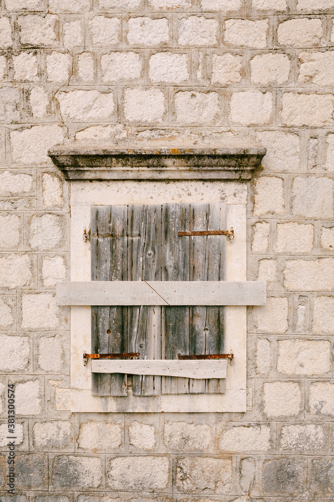 An old building with a window with closed window shutters and hammered boards.