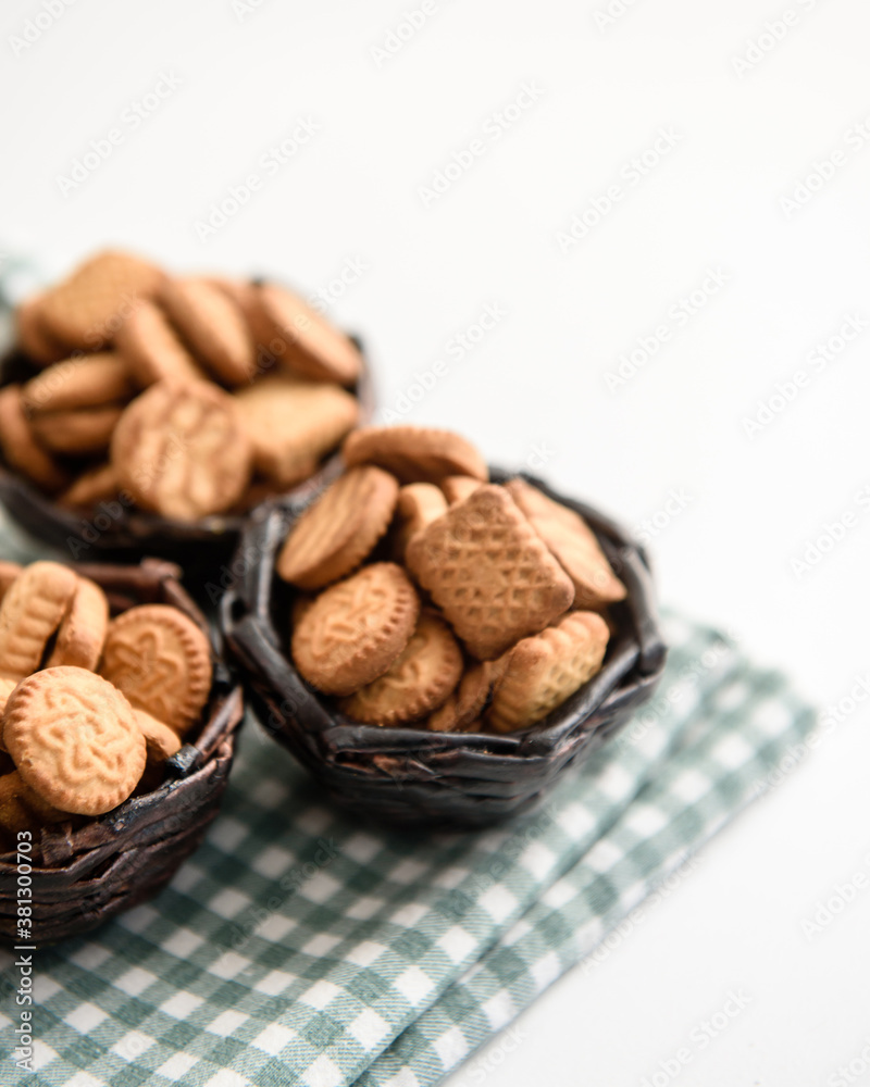 Small cracker cookies in a basket on a linen napkin on a white background Small cracker cookies in a basket on a linen napkin on a white background