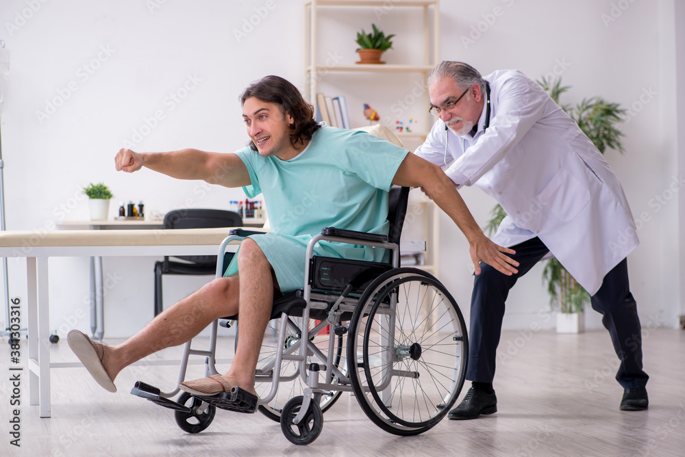 Young male patient in wheel-chair and experienced doctor traumatologist Young male patient in wheel-chair and experienced doctor traumatologist