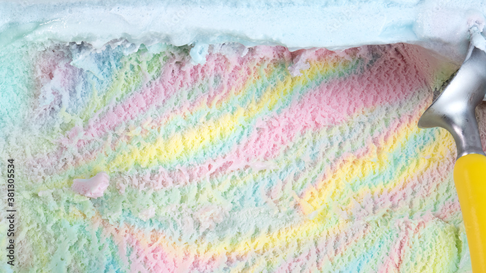 Rainbow colorful flavored ice cream scooped out from container with a spoon, Food concept.