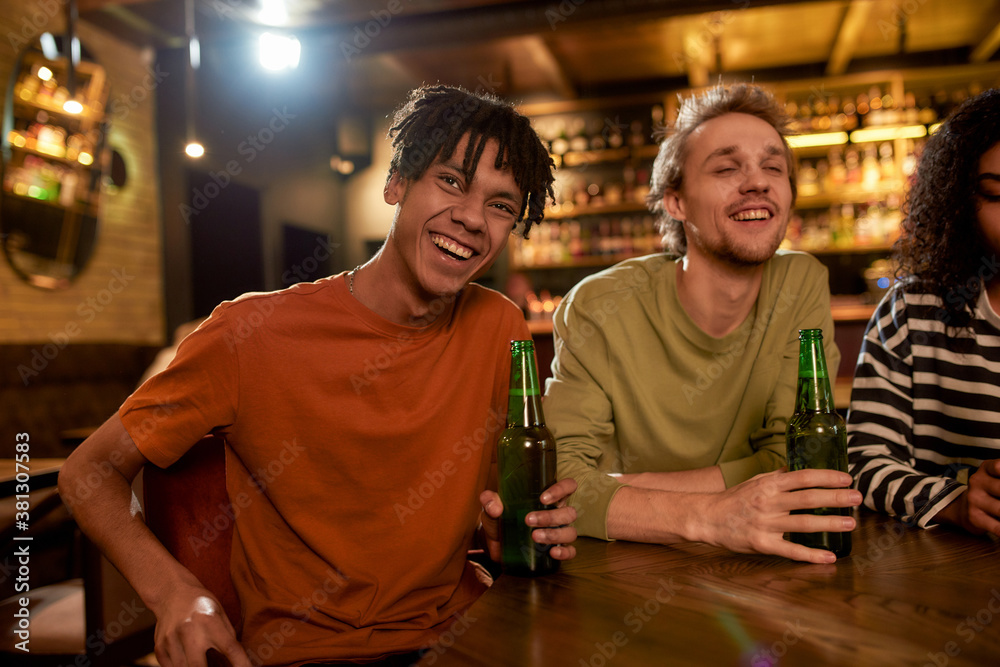 Friends in the bar watching sports match on TV together, drinking beer and cheering for team. People, leisure, friendship and entertainment concept