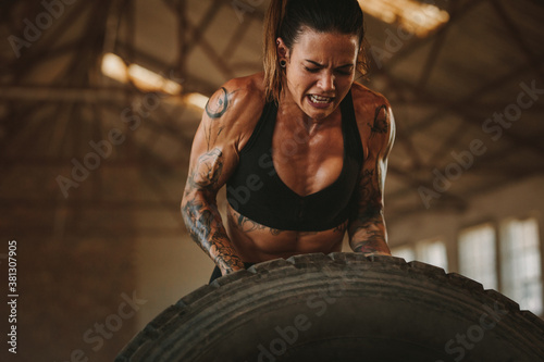 Strong woman performing tyre flipping workout photo