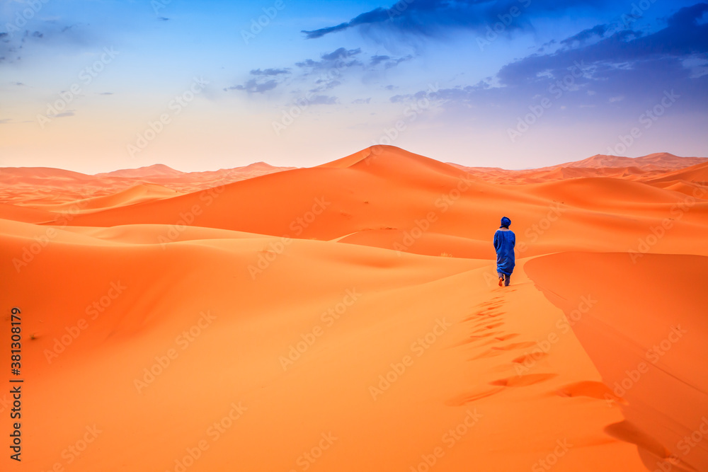 Berber man walking across on desert dunes