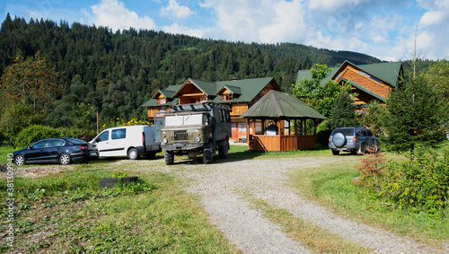 Many cars near the wooden cotage. Ecotourism in the mountains © Aleksander