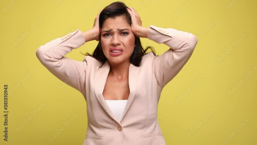 young attractive businesswoman being shocked of what she sees, putting her hands on her head and tearing her hair on yellow background young attractive businesswoman being shocked of what she sees, putting her hands on her head and tearing her hair on yellow background