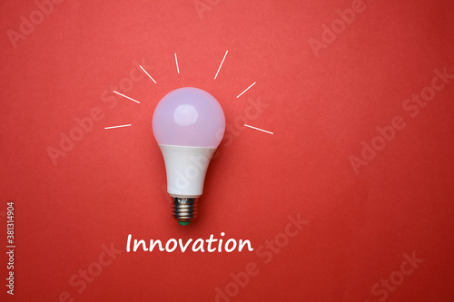 Lightbulb on red background with text on innovation 