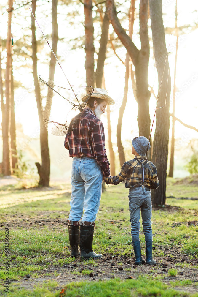 Likable confident bearded grandpa in forest going fishing together with his 10-aged grandson and talking about fishing. Likable confident bearded grandpa in forest going fishing together with his 10-aged grandson and talking about fishing.