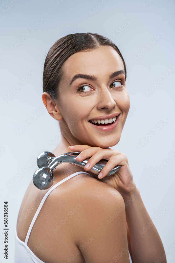 Happy smiling female massaging her shoulder in studio