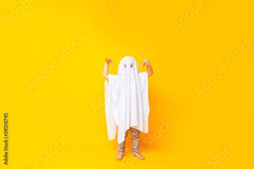 Little kid wearing cute halloween ghost costume on yellow background