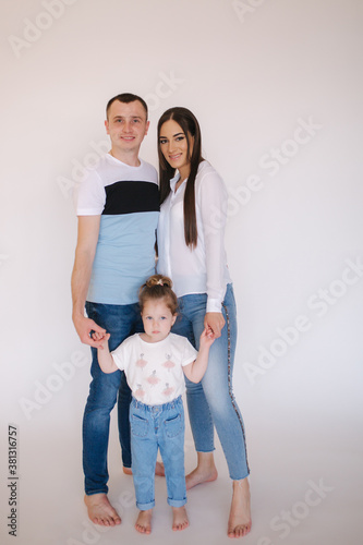 Young family in studio. Mom dad and little daughter in casual style has photosession