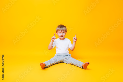 Cute boy on yellow background points with his hand to the side, photo for advertising product © Anastassiya 