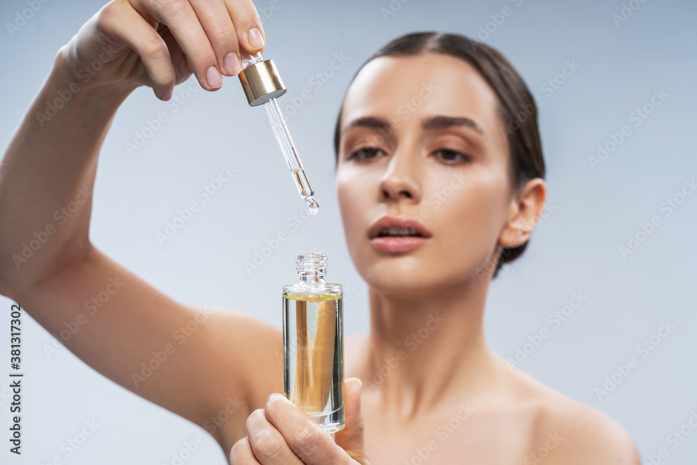 Fototapeta premium Beautiful European woman holding glass bottle in hand