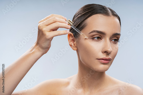 Young beautiful woman applying nature oil under eyes