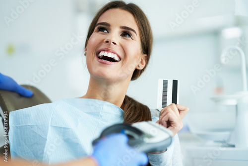 Adult woman paying for visit in dentist office