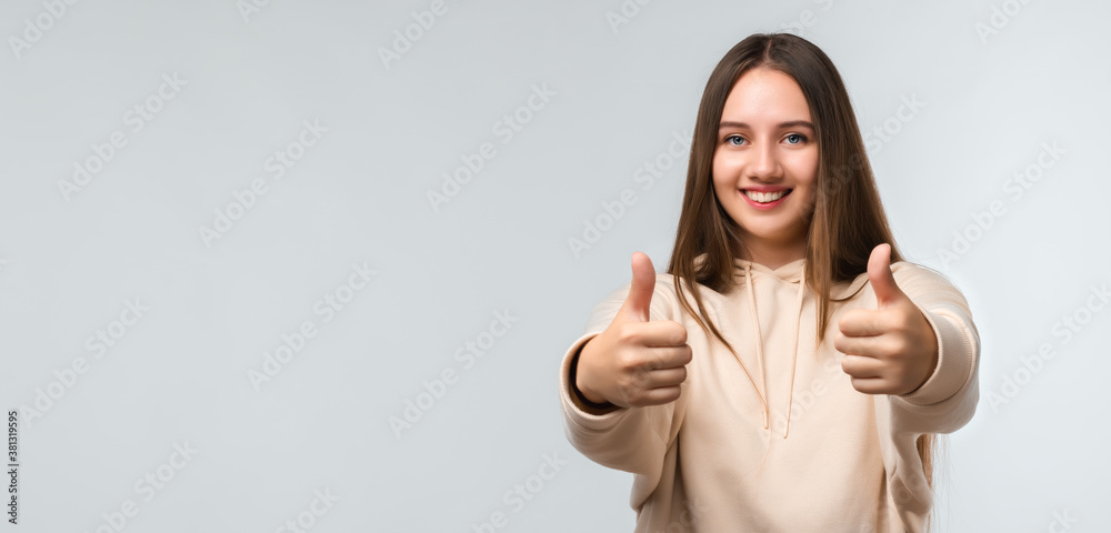 Happy Pretty young woman with long chestnut hair, Smiling and showing thumbs up. Human emotions concept. Copy space