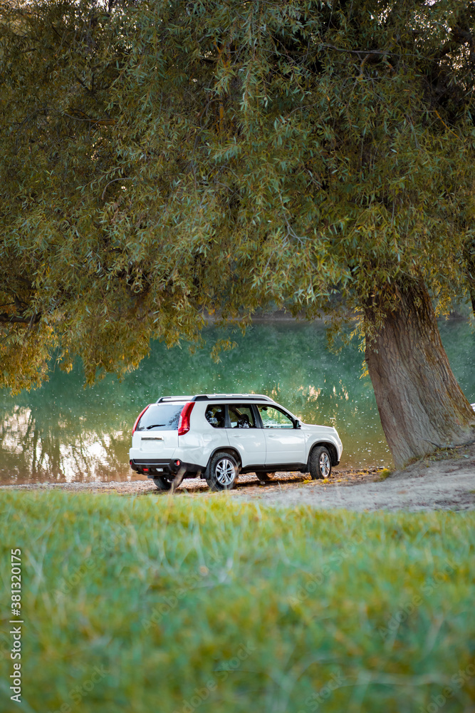 Fototapeta premium view of suv car at river beach on sunset