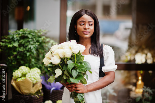 Beautiful african american girl holding bouquet of white roses flowers on dating in the city. Black businesswoman with bunch of flowers. © AS Photo Family