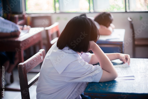 Tired uniform student sleeping in a exam test classroom