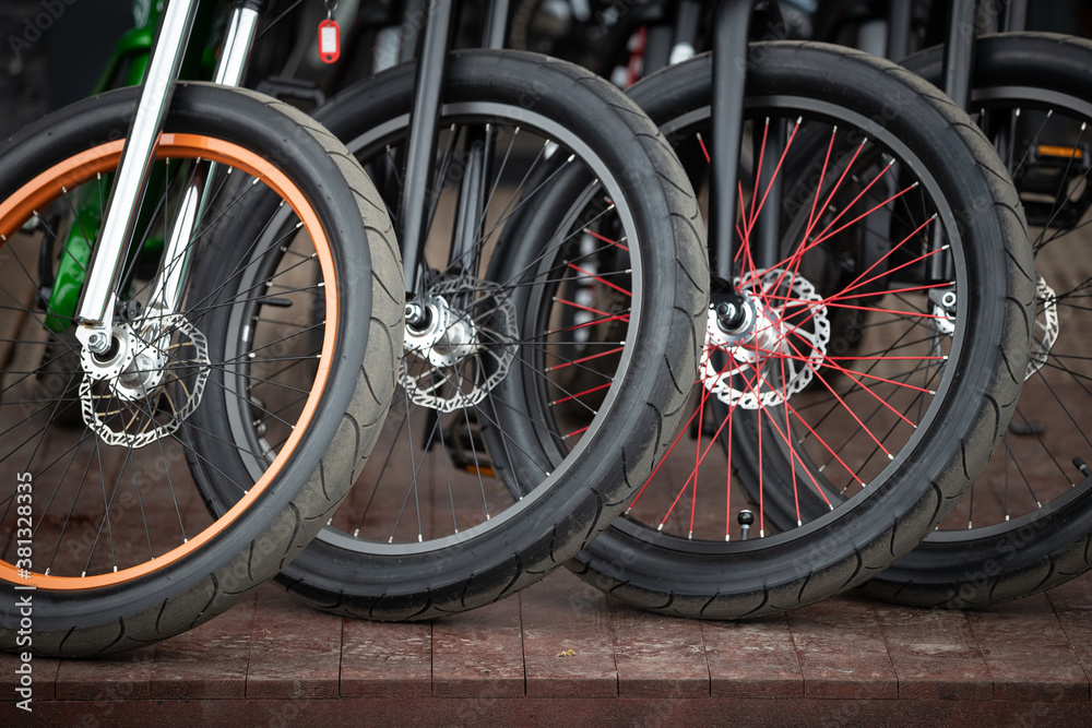 A close-up of the front wheels of a bicycle with disc brakes. Vintage city bicycles parked at a store or rental. A close-up of the front wheels of a bicycle with disc brakes. Vintage city bicycles parked at a store or rental.