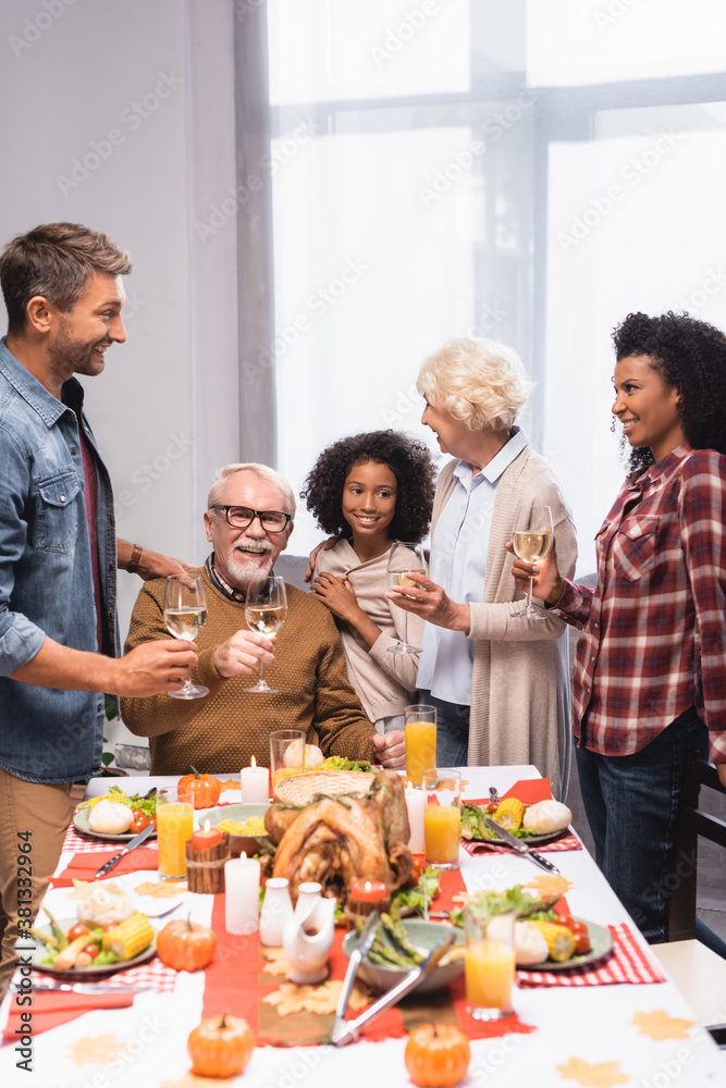 joyful multicultural family holding wine glasses while celebrating thanksgiving day