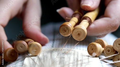 Video detail of bobbin lace handcrafting. Woman hands braiding threads to make a pattern.
