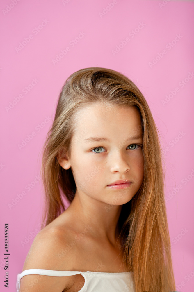 portrait of a gentle 9-year-old long-haired girl in a light T-shirt against a lilac wall portrait of a gentle 9-year-old long-haired girl in a light T-shirt against a lilac wall