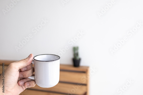White small mug of coffee in a white cozy room in the morning.